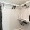 a room with a white wall and a black shelf with clothes